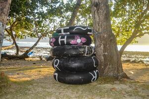 Stapel von benutzt Reifen benutzt wie Bojen auf Abonnieren Strand foto