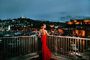 ein elegant Mädchen im ein rot Abend Kleid auf das Straßen von das Nacht Stadt von marseille.a Frau im ein rot Abend Kleid im Frankreich foto