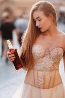 ein Braut im ein Hochzeit Kleid mit lange Haar und ein trinken Flasche im das alt Stadt, Dorf von Breslau. Hochzeit Foto schießen im das Center von ein alt Polieren Stadt Breslau, Polen