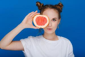 überrascht, das Lachen Mädchen hält das Grapefruit mögen Ohren. vegan Lebensstil. lächelnd Frau , Essen Konzept.Diät organisch , Gewicht Verlust und gesund Lebensmittel. Smoothies und frisch Saft. foto