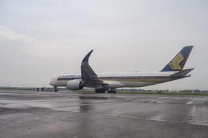 ein Airbus a350-941 breit Körper Flugzeug Zugehörigkeit zu Singapur Fluggesellschaft ist Sein abgeschleppt mit ein Rückstoß Auto auf das Schürze von Juanda International Flughafen, surabaya im Sidoarjo, Indonesien, 6 Januar 2024 foto