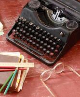 klassisch Metall Jahrgang Schreibmaschine auf alt rot gemalt Holz mit Brille und alt Notizbücher foto