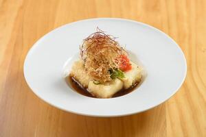 japanisch Essen Agedashi - Das ist die Antwort Tofu serviert im aromatisch tsuyu Soße im ein Weiß Schüssel oben Aussicht auf Holz Hintergrund foto