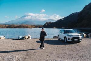 Frau Tourist genießen mit Fuji Berg beim See Shoji, glücklich Reisender Besichtigung montieren Fuji und Straße Ausflug Fuji fünf Seen. Wahrzeichen zum Touristen Attraktion. Japan reisen, Ziel und Ferien foto