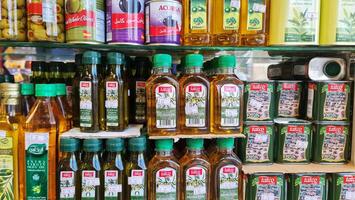 Medina, Saudi Arabien auf März 1 2024. verschiedene Marken von extra Jungfrau Olive Öl, einer von welche ist tatco und Hallo, und Andere im Glas Flaschen, Plastik Flaschen und Büchsen. im ein Lebensmittelgeschäft Geschäft foto