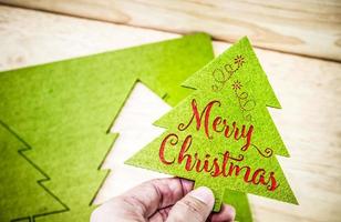 Hand, die grünen Weihnachtsbaum mit Frohe Weihnachten-Wort hält foto