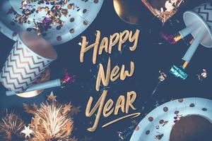 Frohes neues Jahr Hand Pinselstrich Schrift auf Marmortisch mit Partytasse, Partygebläse, Lametta, Konfetti foto
