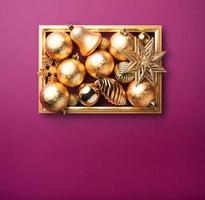 glänzende goldene Weihnachtsdekorationskugel und Stern mit goldenem Rahmen in lila Luxus foto