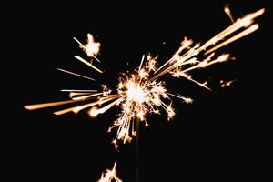 brennende Wunderkerze auf schwarzem Hintergrund in der Nacht, Feiertagsfeier foto