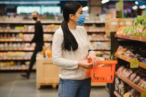 alarmiert weiblich trägt medizinisch Maske gegen Coronavirus während Lebensmittelgeschäft Einkaufen im Supermarkt oder speichern- Gesundheit, Sicherheit und Pandemie Konzept - - jung Frau tragen schützend Maske und Bevorratung Lebensmittel. foto