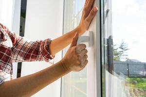 das Hand hält das Griff von ein Plastik doppelt verglast Fenster, Schließen und Öffnung das Fenster mit ein rotierend Mechanismus, das Position von das Griff zum Belüftung, Mikrobelüftung foto