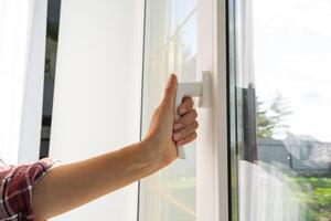 das Hand hält das Griff von ein Plastik doppelt verglast Fenster, Schließen und Öffnung das Fenster mit ein rotierend Mechanismus, das Position von das Griff zum Belüftung, Mikrobelüftung foto