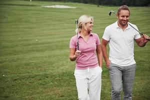 sportliches Paar beim Golfen auf einem Golfplatz, sie stehen bis zum nächsten Loch foto