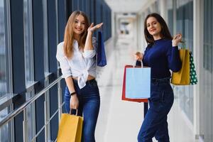 zwei Freundinnen auf Einkaufen gehen auf Einkaufen Center mit Taschen foto