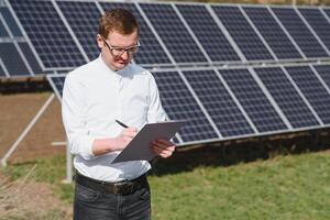 Solar- Paneele und Blau Himmelmann Stehen in der Nähe von Solar- Tafeln. Solar- Panel produziert Grün, ökologisch freundlich Energie von das Sonne. foto