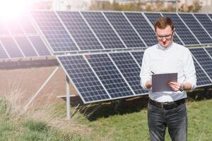 Solar- Paneele und Blau Himmelmann Stehen in der Nähe von Solar- Tafeln. Solar- Panel produziert Grün, ökologisch freundlich Energie von das Sonne. foto