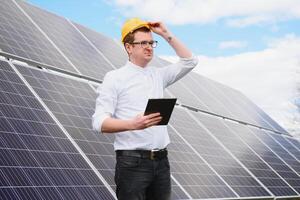 Solar- Paneele und Blau Himmelmann Stehen in der Nähe von Solar- Tafeln. Solar- Panel produziert Grün, ökologisch freundlich Energie von das Sonne. foto