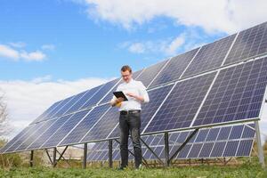 Solar- Paneele und Blau Himmelmann Stehen in der Nähe von Solar- Tafeln. Solar- Panel produziert Grün, ökologisch freundlich Energie von das Sonne. foto