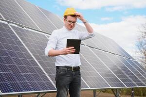 Solar- Paneele und Blau Himmelmann Stehen in der Nähe von Solar- Tafeln. Solar- Panel produziert Grün, ökologisch freundlich Energie von das Sonne. foto