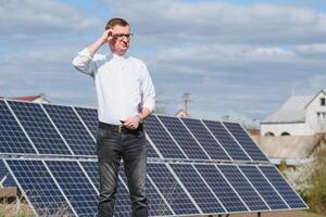 Solar- Paneele und Blau Himmelmann Stehen in der Nähe von Solar- Tafeln. Solar- Panel produziert Grün, ökologisch freundlich Energie von das Sonne. foto