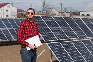 Solar- Paneele und Blau Himmelmann Stehen in der Nähe von Solar- Tafeln. Solar- Panel produziert Grün, ökologisch freundlich Energie von das Sonne. foto