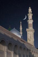 ein Moschee mit das voll Mond im das Himmel. Masjid Nabi von Medina, Moschee beim Nacht. Masjid Nabi von Medina. Grün Kuppel und Mond.. foto
