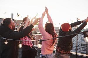 Ein neuer Tag hat begonnen. Hände hoch. junge Leute verbringen sonnigen Herbsttag auf dem Dach mit Gitarre und Getränken foto