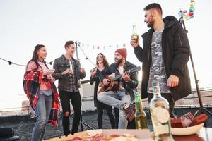 Freizeit haben. Tisch mit Essen. Wochenende auf dem Dach mit Gitarre, Alkohol und Pizza foto