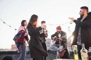 jedermanns Lieblingslied. Dachparty mit etwas Alkohol und Gitarrenspiel. Sonnenschein dahinter foto