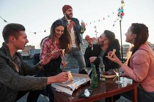 Zeit zum Singen. das denkt zumindest der Typ mit dem roten Hut. Pizza essen auf der Dachparty. Gute Freunde haben Wochenende mit leckerem Essen und Alkohol foto