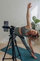 ein 50 Jahre alt Frau tun online Yoga beim Zuhause foto