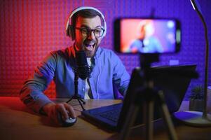 Streamer ist Streaming online Inhalt, Metaverse ar VR, Spiele und Esport Konzept.glücklich Mann Spieler tragen Kopfhörer Wettbewerb Video Spiel online mit Laptop Computer im bunt Neon- Beleuchtung. foto