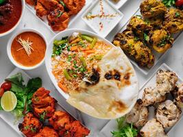 sortiert berühmt indisch und pakistanisch Essen Tabelle Gemüse Biryani, Butter Huhn, Paneer Hähnchen Tikka boti Kebab, Kalk, Kali Mirchi, Tomate Soße, Raita, Roti, Salat, oben Aussicht auf grau Hintergrund foto