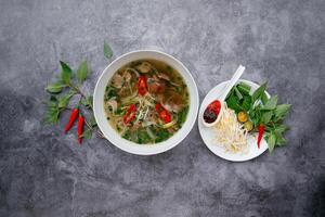 frisch heiß Rindfleisch pho mit Salat Blätter serviert im Schüssel isoliert auf dunkel grau Hintergrund oben Aussicht von japanisch Essen foto