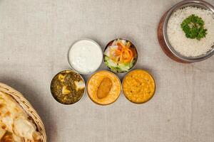 Gemüse Thali mit Daal, Palak Paneer, Raita, Salat, Curry, brot, Roti und einfach Reis serviert im ein Gericht isoliert auf Tabelle oben Aussicht von indisch Gewürze Essen foto