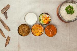Bangal, indisch Fleisch Thali mit Korma, Hähnchen Curry, Salat, Raita einfach Reis serviert im ein Gericht isoliert auf Tabelle oben Aussicht von indisch Gewürze Essen foto