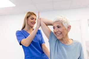 Arzt oder Physiotherapeut Arbeiten Prüfung Behandlung verletzt Arm von Senior weiblich geduldig, Dehnen und Übung, tun das Rehabilitation Therapie Schmerzen im Klinik. foto