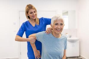 Arzt oder Physiotherapeut Arbeiten Prüfung Behandlung verletzt Arm von Senior geduldig, Dehnen und Übung, tun das Rehabilitation Therapie Schmerzen im Klinik. foto