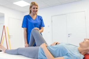 Physiotherapeut Arbeiten mit geduldig im Klinik, Nahaufnahme. ein modern Rehabilitation Physiotherapie Arbeiter mit Senior Klient, physisch Therapeut Dehnen geduldig Knie foto