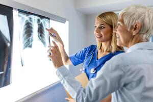 Radiologie und Medizin Konzept. Arzt erklären das Ergebnisse von Scan Lunge auf Bildschirm zu Senior geduldig. foto