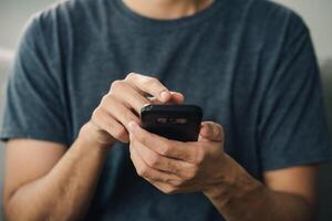 ein Mann ist halten ein Zelle Telefon und ist suchen beim es foto