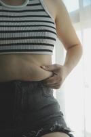 Frauen Körper Fett Bauch. fettleibig Frau Hand halten übermäßig Bauch fett. Diät Lebensstil Konzept zu reduzieren Bauch und gestalten oben gesund Bauch Muskel. foto