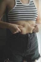 Frauen Körper Fett Bauch. fettleibig Frau Hand halten übermäßig Bauch fett. Diät Lebensstil Konzept zu reduzieren Bauch und gestalten oben gesund Bauch Muskel. foto