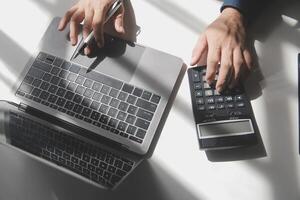 geschäftsmann, der am schreibtischbüro arbeitet und einen taschenrechner verwendet, um die zahlen zu berechnen, finanzbuchhaltungskonzept foto