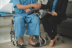 Mittelteil von weiblich Krankenschwester Überprüfung Blut Druck von Frau Sitzung auf Rollstuhl im Klinik foto