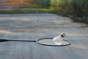 Weiß Sahne Badminton Federbälle auf Badminton Schläger, verschwommen Bäume Hintergrund, Konzept zum draussen Badminton spielen im kostenlos mal, Sanft und selektiv Fokus. foto