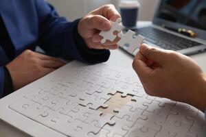 im Hände von Geschäftsleute und Investoren Sie halt Puzzle Stücke zu stellen zusammen im richtig Weg zu machen das Puzzle Stücke symbolisieren ihr Beteiligung im Geschäft Unternehmungen. wagen Hauptstadt Symbol Konzept foto