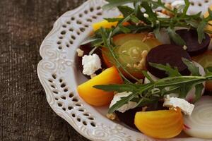 gesund Zuckerrüben Salat mit Rot, Weiss, golden Rüben, Rucola, Nüsse, Feta Käse auf hölzern Hintergrund foto