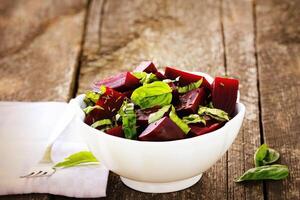 Rote Beete gehackt zum Salat mit Basilikum und Dill Saat im Schüssel auf rustikal hölzern Tabelle foto