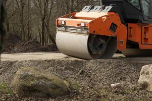 Orange und schwarz Straße Walze gelegen im Konstruktion Seite? ˅ foto